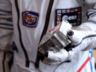 Closeup of an astro pi in an astronauts hand.